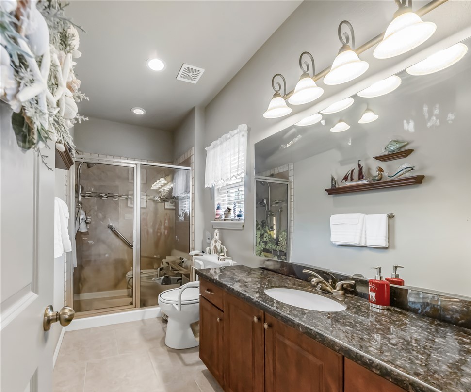 3815 Harvey Road College Station, TX 77845 - Photo 18 of 24 a bathroom with a granite countertop sink a toilet a mirror a vanity and shower