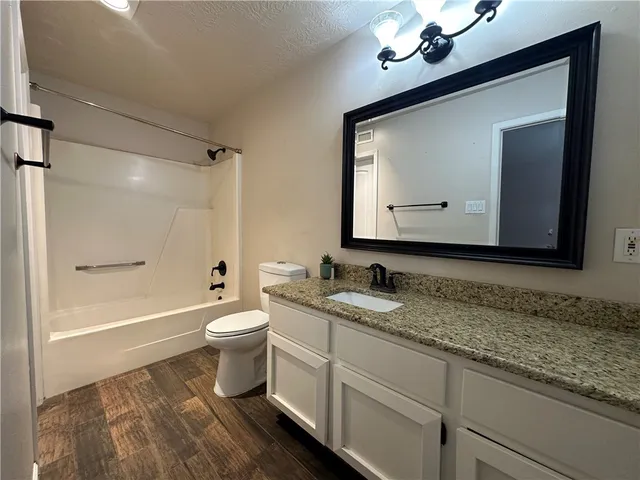 a bathroom with a toilet a sink a tub and a mirror
