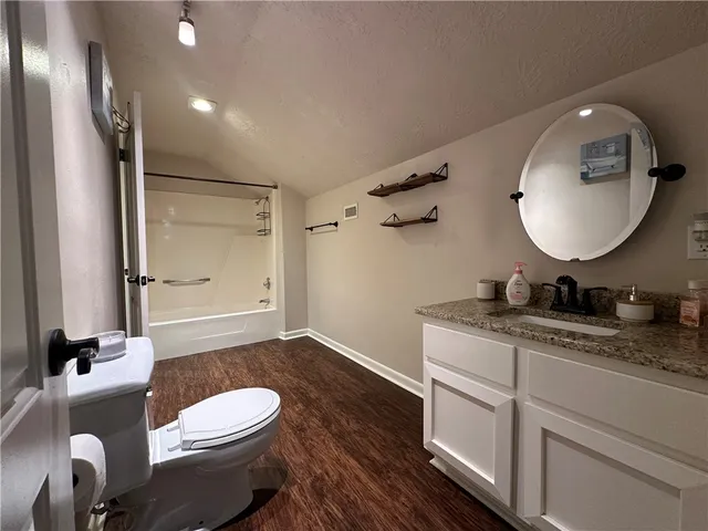 a bathroom with a granite countertop toilet sink and mirror