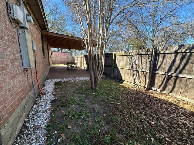 a view of a backyard with large trees and wooden fence
