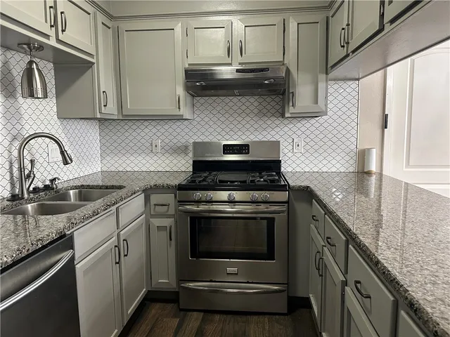 a kitchen with stainless steel appliances granite countertop a sink stove and cabinets