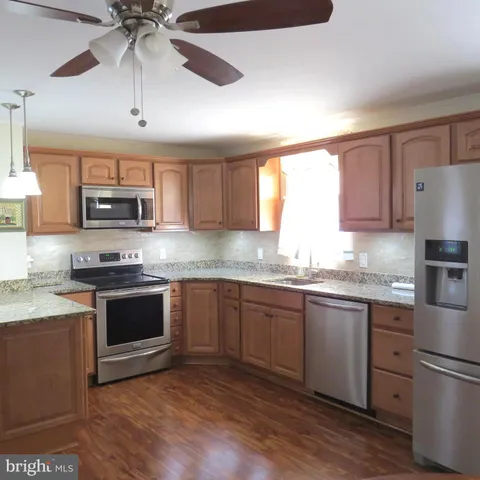 a kitchen with granite countertop a sink cabinets and stainless steel appliances