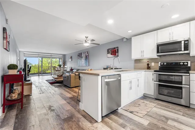 a kitchen that has a lot of white cabinets and stainless steel appliances