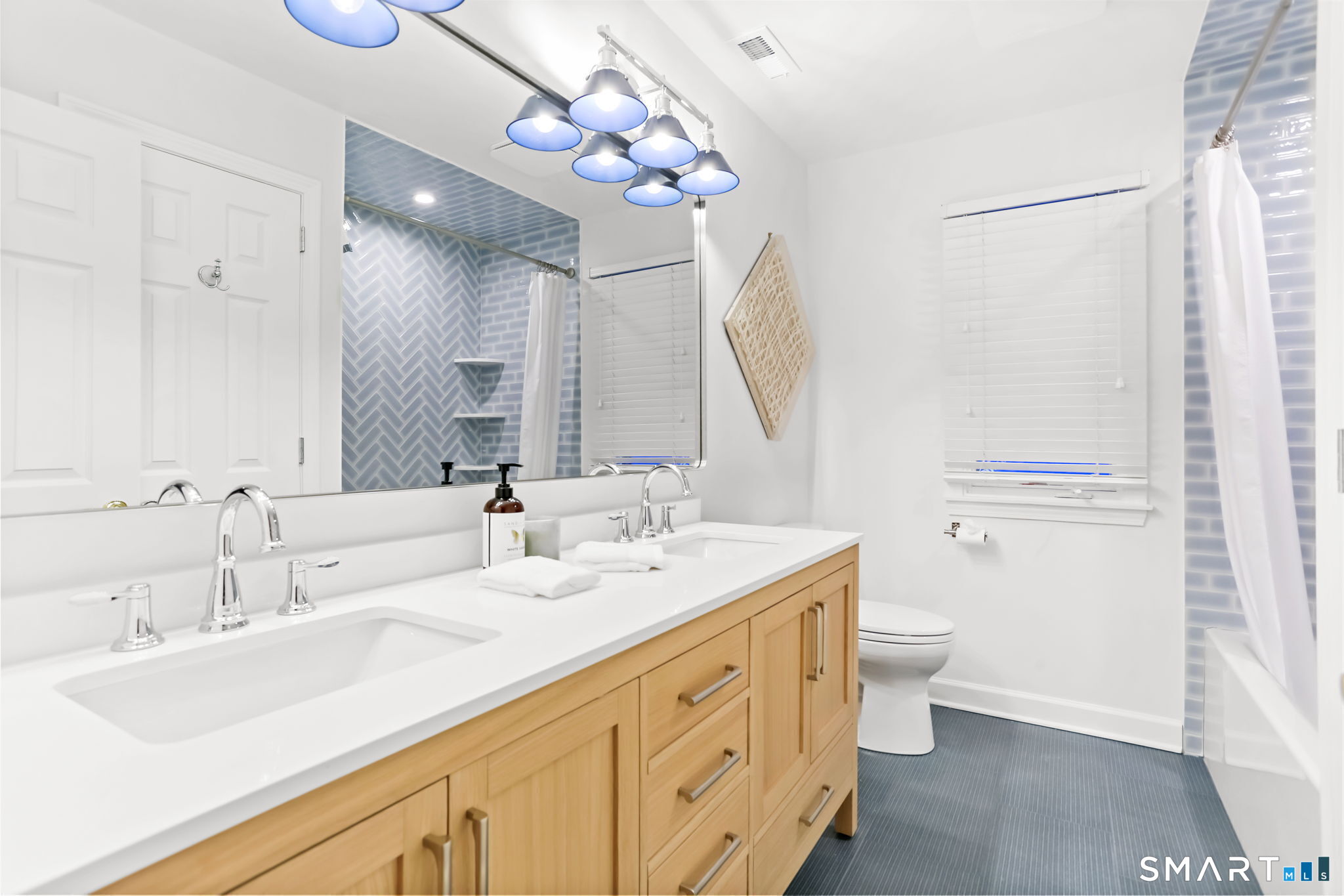 1149 Fairfield Beach Road Fairfield, CT 06824 - Photo 25 of 40 Newly updated hall bath w/favorite double vanities and tub shower combination tiled in a neat herringbone style w/ popular denim tile