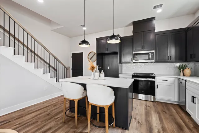 a kitchen with stainless steel appliances a dining table chairs refrigerator and sink