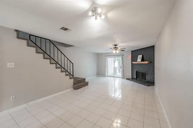 a view of an empty room with chandelier fan and fire place