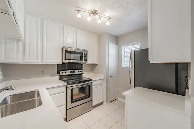 a kitchen with stainless steel appliances granite countertop white cabinets and refrigerator