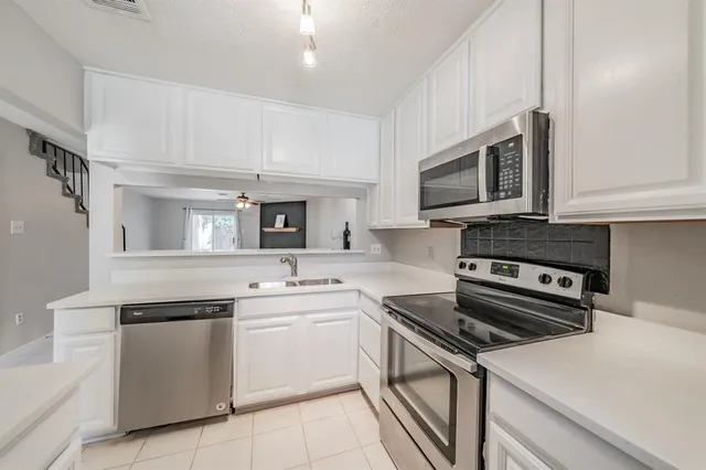 a kitchen with cabinets stainless steel appliances and a counter space