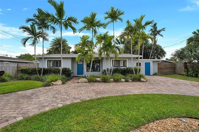 a view of a house with a yard and palm trees