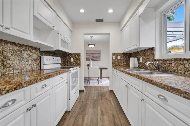 a large kitchen with stainless steel appliances granite countertop a lot of counter space and wooden floors