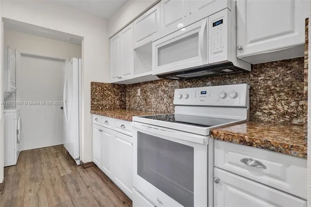 a kitchen with granite countertop cabinets appliances and a wooden floor