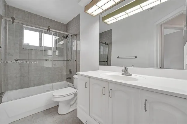 a bathroom with a granite countertop sink a toilet and shower