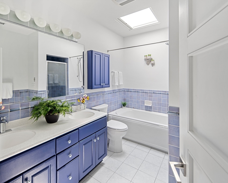 85 Sherman Street, Unit 10 Cambridge, MA 02140 - Photo 11 of 21 a bathroom with a double vanity sink toilet mirror and bathtub