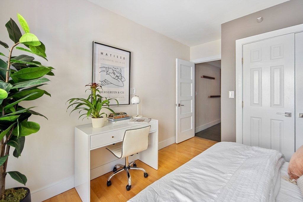 85 Sherman Street, Unit 10 Cambridge, MA 02140 - Photo 10 of 21 a bedroom with a bed table chair and a potted plant