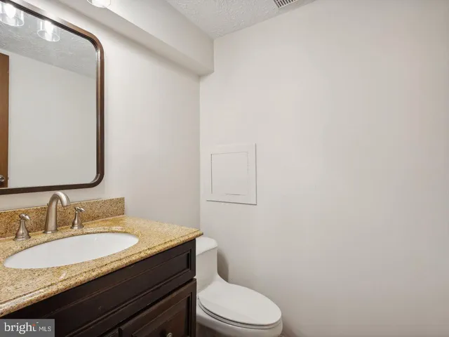 a bathroom with a granite countertop sink toilet and mirror