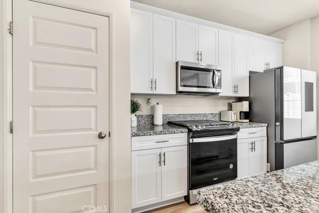 a kitchen with white cabinets and stainless steel appliances
