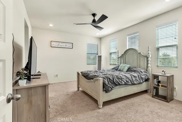 a spacious bedroom with a bed and a flat screen tv