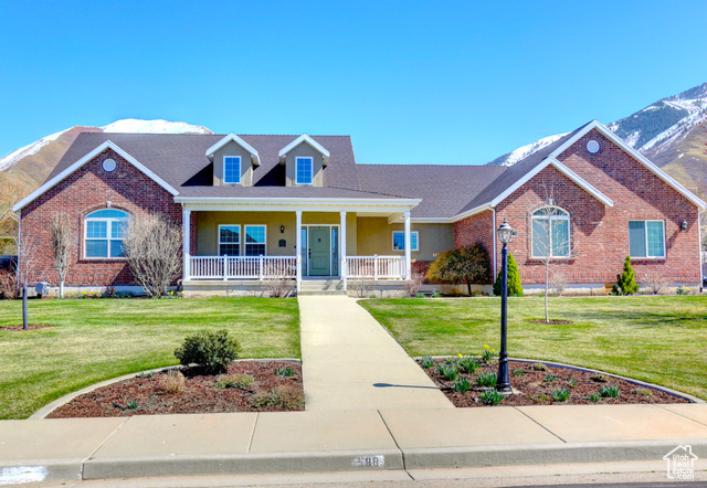588 North 1200th Street East Mapleton, UT 84664 - Photo 1 of 1 View of front facade featuring a front lawn, a mountain view, covered porch, and brick siding