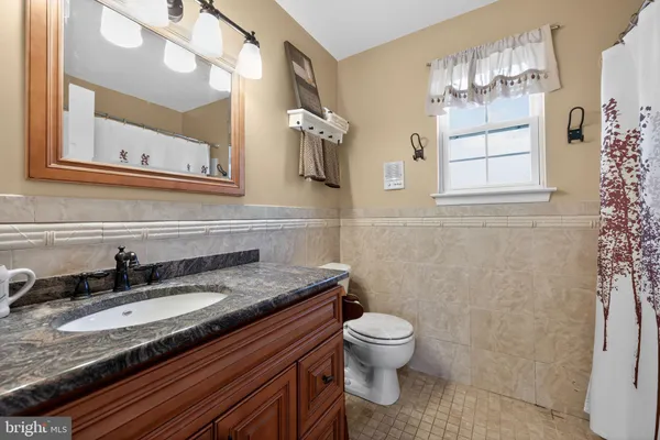 a bathroom with a granite countertop sink and a toilet