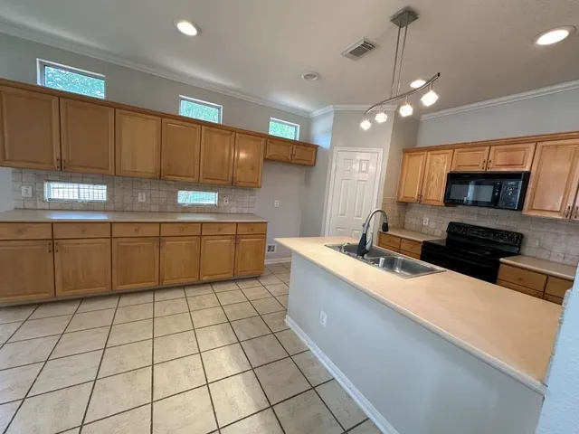 a large kitchen with stainless steel appliances a sink a counter top space cabinets and a window