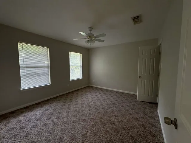 an empty room with windows and fan