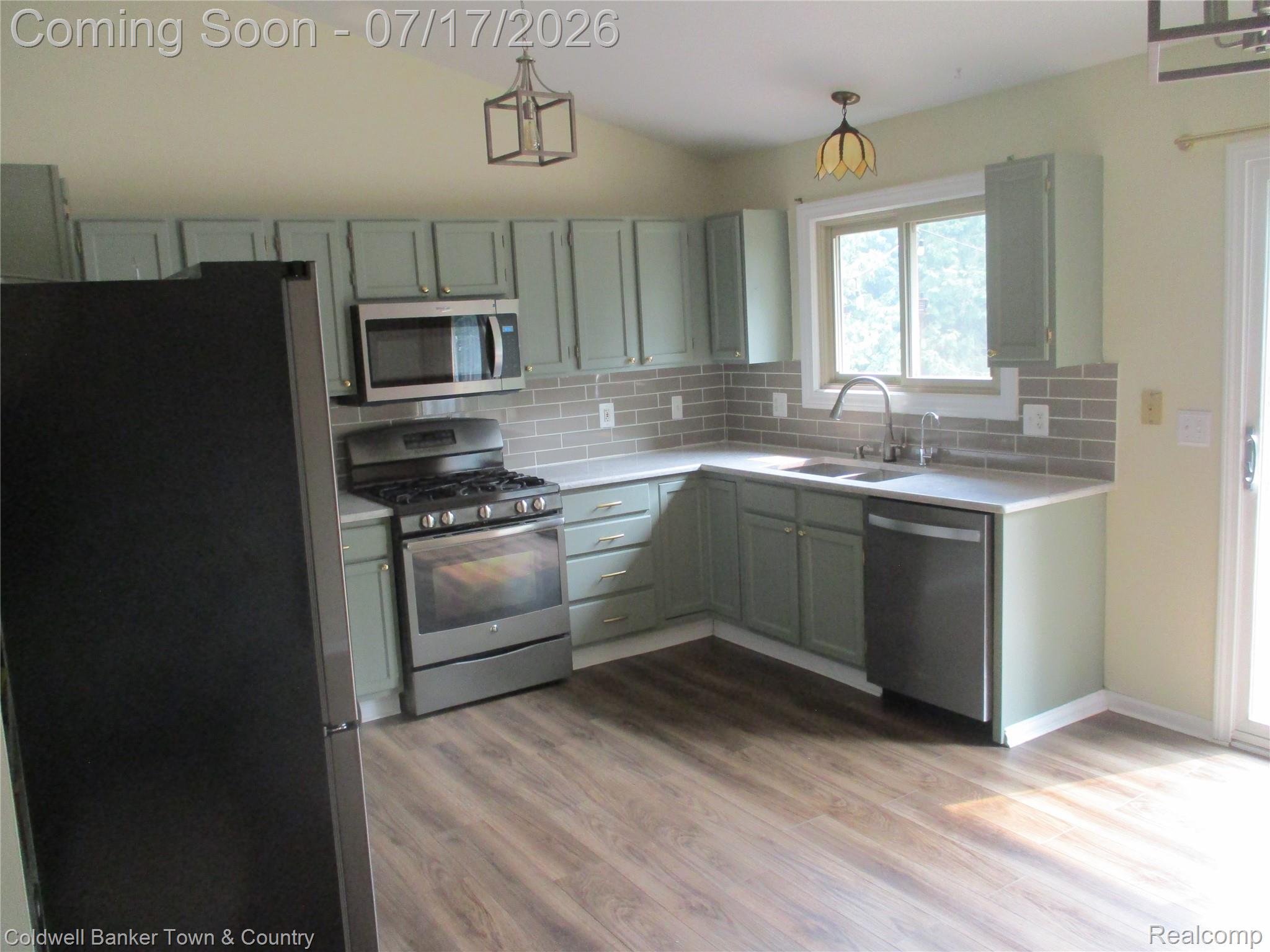 1996 Triangle Lake Road Howell, MI 48843 - Photo 6 of 32 Free flowing Kitchen ,featuring stainless steel appliances, light-toned countertops, subway tile backsplash, and wood-finish flooring