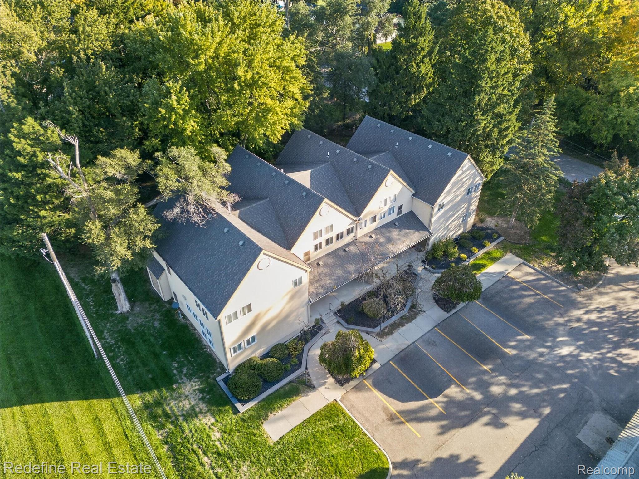 27971 Rollcrest Road, Unit 9 Farmington, MI 48334 - Photo 23 of 25 Expansive paved parking area, lush green lawn, and mature trees surround the property