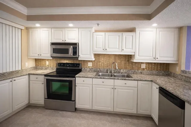 a kitchen with granite countertop white cabinets sink and stainless steel appliances