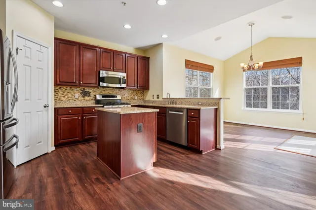 a kitchen with stainless steel appliances granite countertop wooden floors and sink