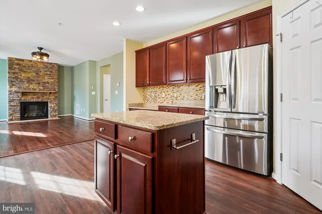 a kitchen with stainless steel appliances granite countertop a refrigerator a stove and a wooden floors
