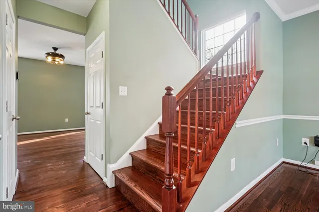 a view of an empty room with wooden floor and a ceiling fan