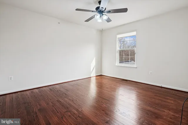 a view of an empty room with window and wooden floor