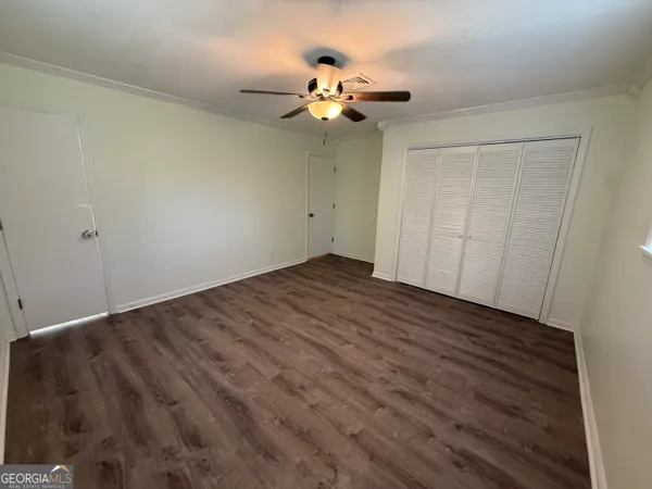 a view of an empty room with wooden floor and a chandelier fan