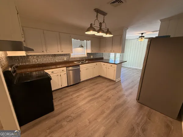 a large kitchen with granite countertop a stove top oven a sink a counter space and cabinets