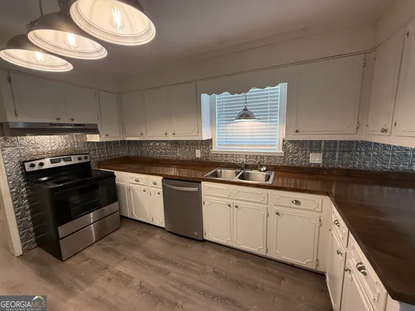 a kitchen with granite countertop a stove a sink dishwasher and cabinets with wooden floor