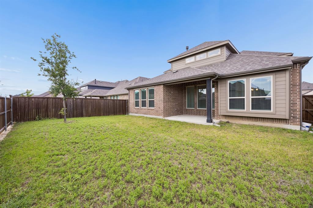 1303 Wheelwright Drive Forney, TX 75126 - Photo 36 of 39 Spacious backyard featuring a privacy fence, covered patio, brick exterior, and multiple large windows