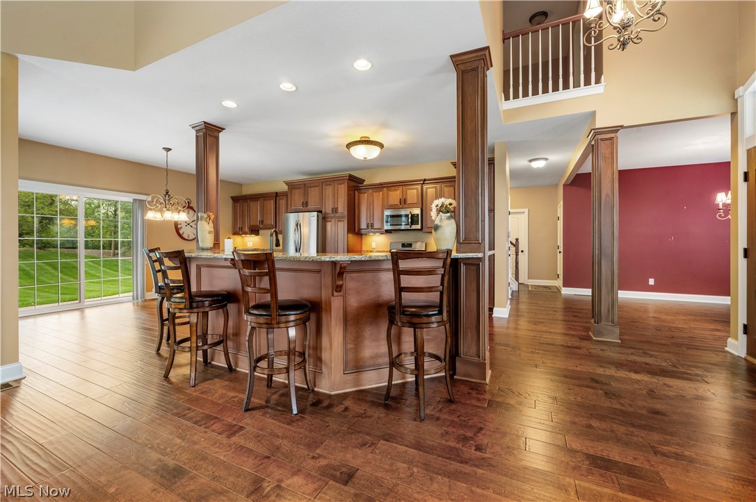 3356 Huntcliffe Road Northeast Canton, OH 44721 - Photo 22 of 50 Kitchen with kitchen peninsula, dark wood-type flooring, stainless steel appliances, ornate columns, and a kitchen breakfast bar
