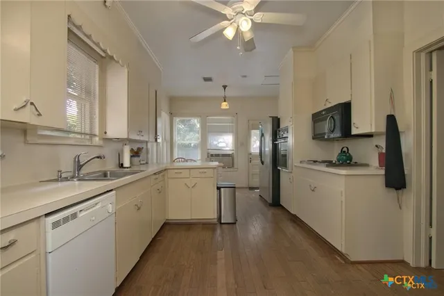 a kitchen with a sink dishwasher and white cabinets with wooden floor
