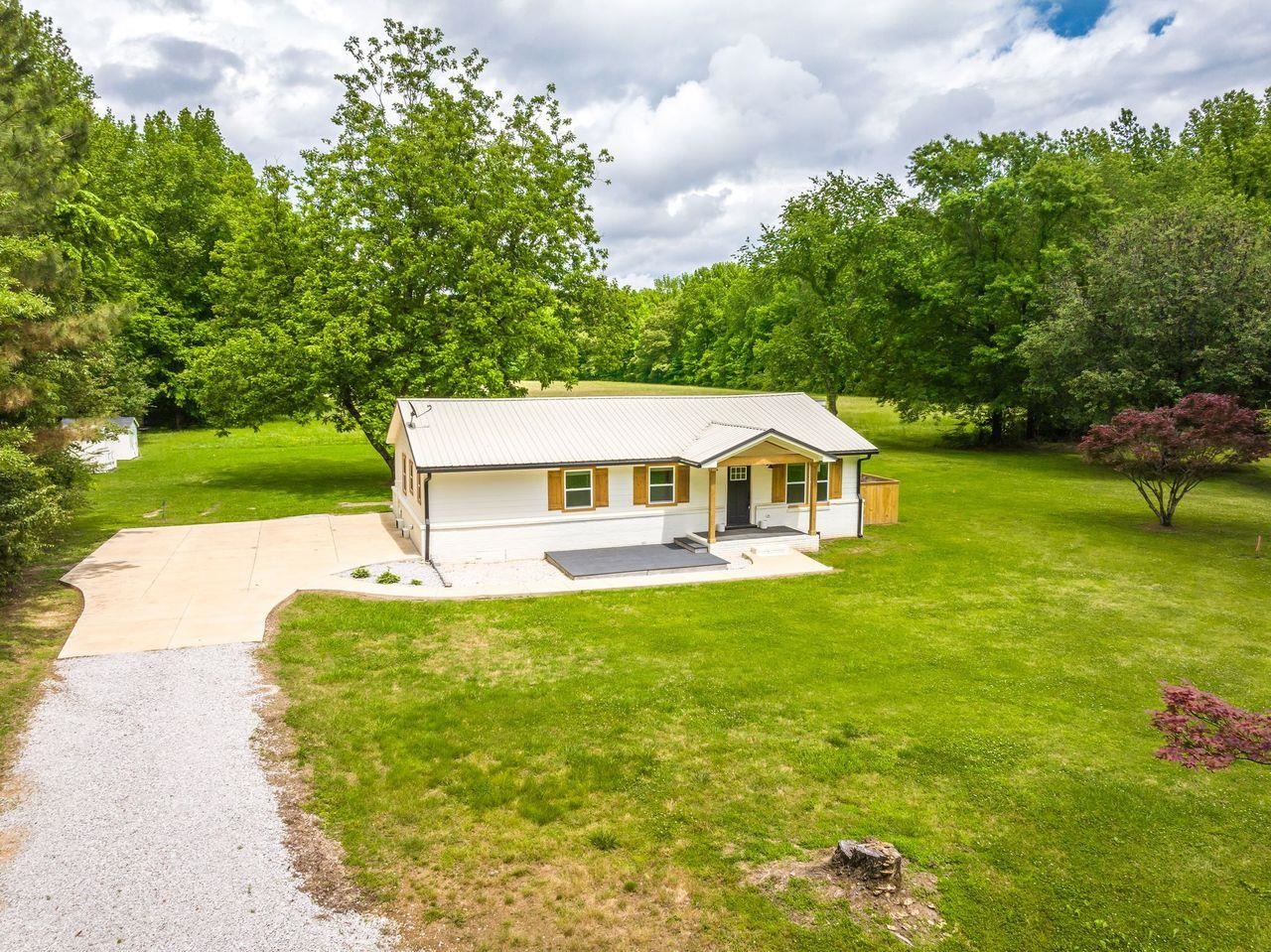 a white house with a big yard and large trees
