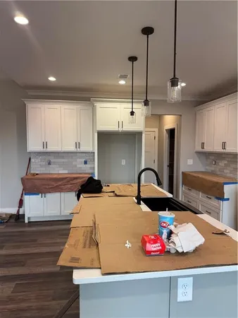 a kitchen with kitchen island granite countertop a sink a counter space appliances and cabinets