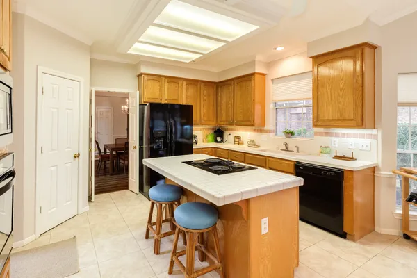 a kitchen with stainless steel appliances kitchen island a table chairs sink refrigerator and cabinets