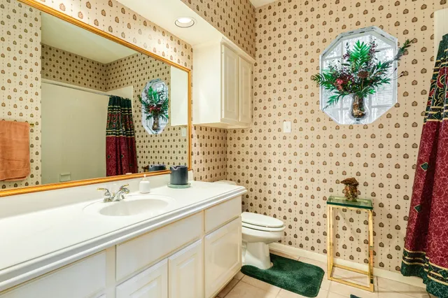 a bathroom with a granite countertop toilet a sink and a mirror