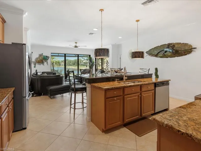 a kitchen with kitchen island granite countertop a sink a counter top space appliances and cabinets