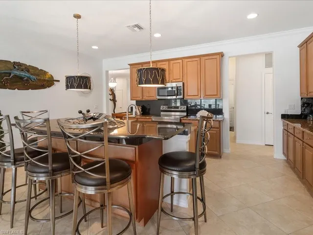 a kitchen with stainless steel appliances kitchen island granite countertop a stove a sink and a refrigerator