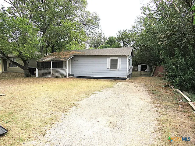 a front view of house with yard and trees in the background