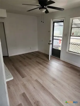 an empty room with wooden floor cabinet and windows