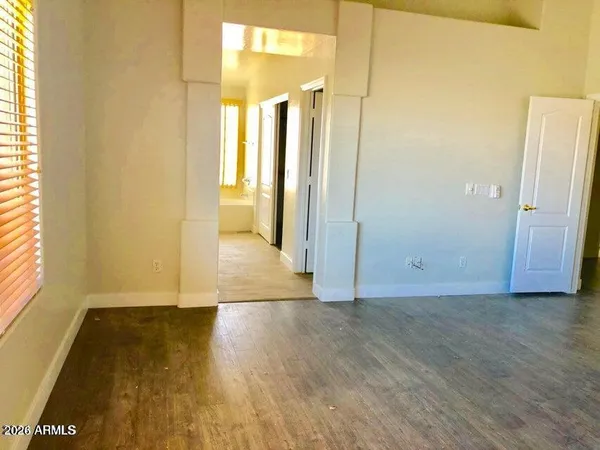 a view of an empty room with wooden floor and a window