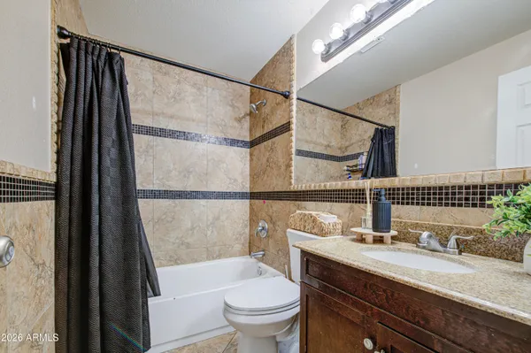 a bathroom with a granite countertop sink a toilet a mirror and shower