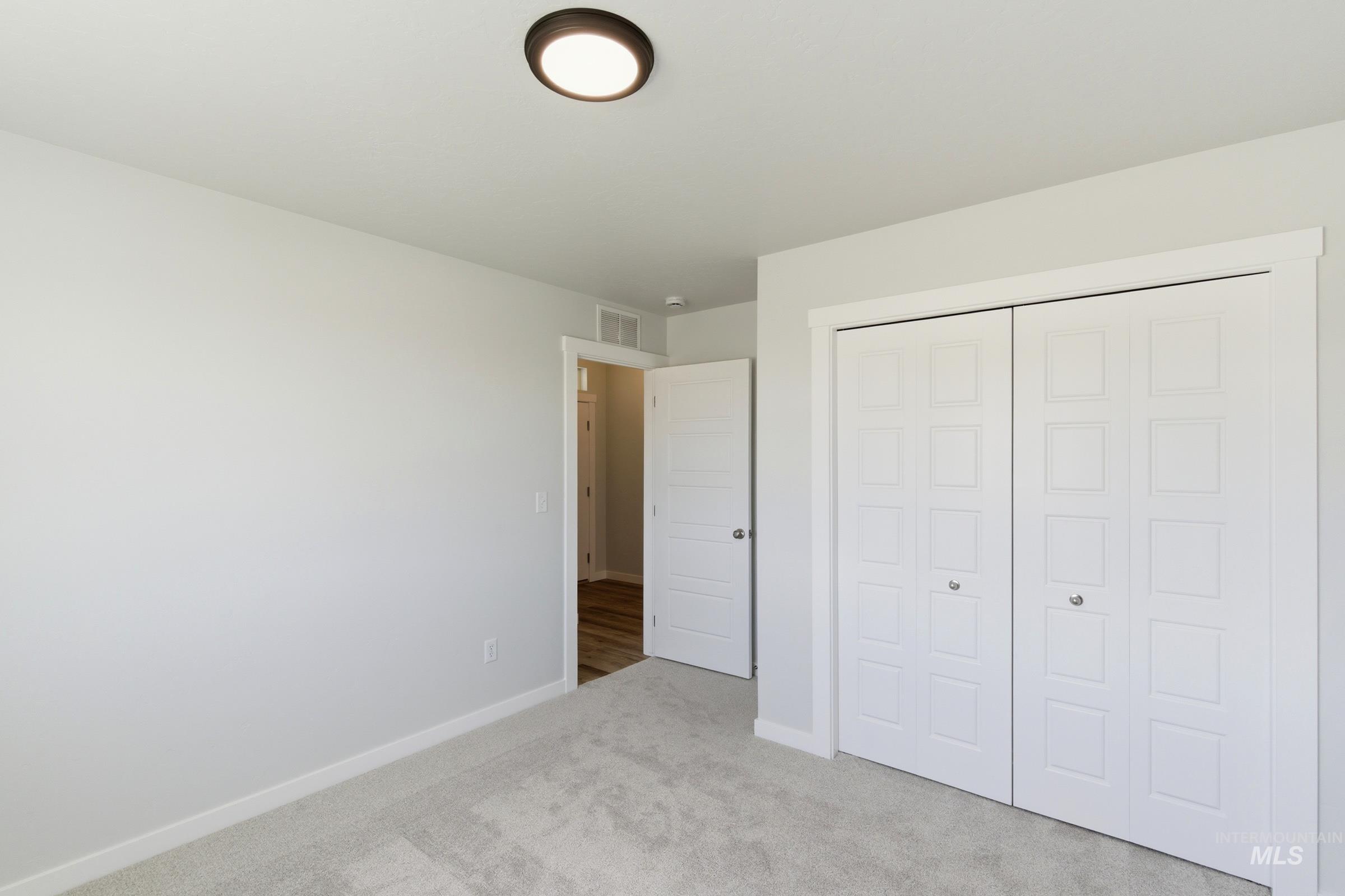 8317 South Tyrion Way Kuna, ID 83634 - Photo 13 of 22 Bedroom featuring plush carpeting, crisp white trim, and a bi-fold closet with decorative paneling