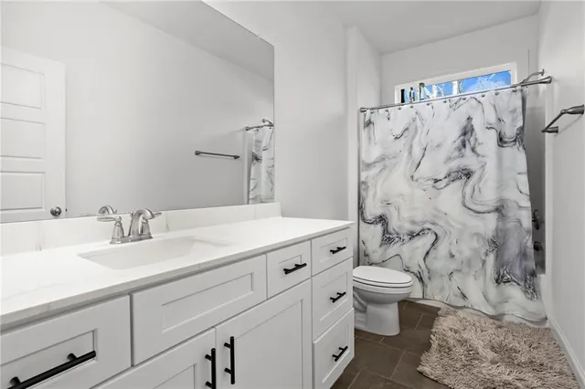 a bathroom with a granite countertop toilet a sink and a shower